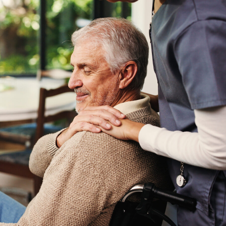 A Serenity Care carer with a hand on a client's shoulder at home